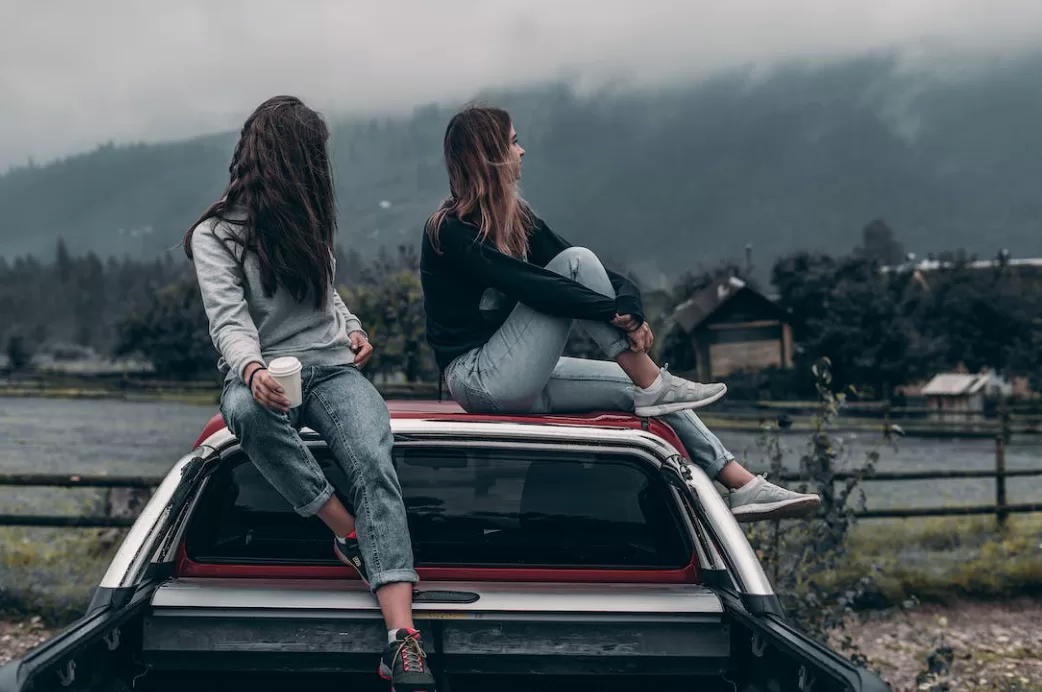 Two women sitting on a car roof