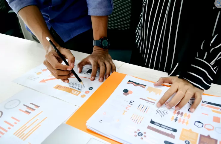 Two people strategizing over printed sheets with data