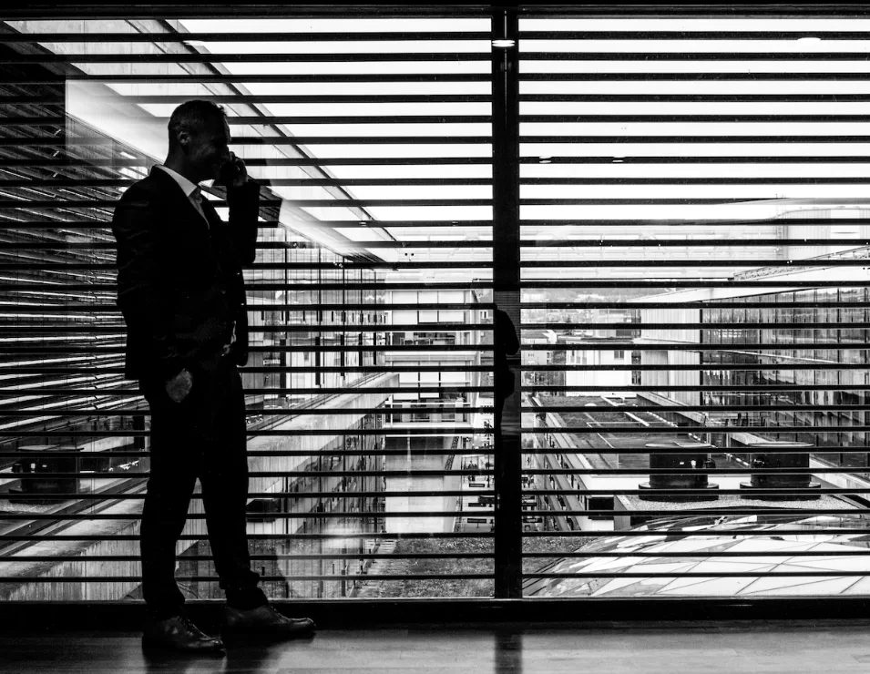 a black&white picture of a man talking on the phone in his office