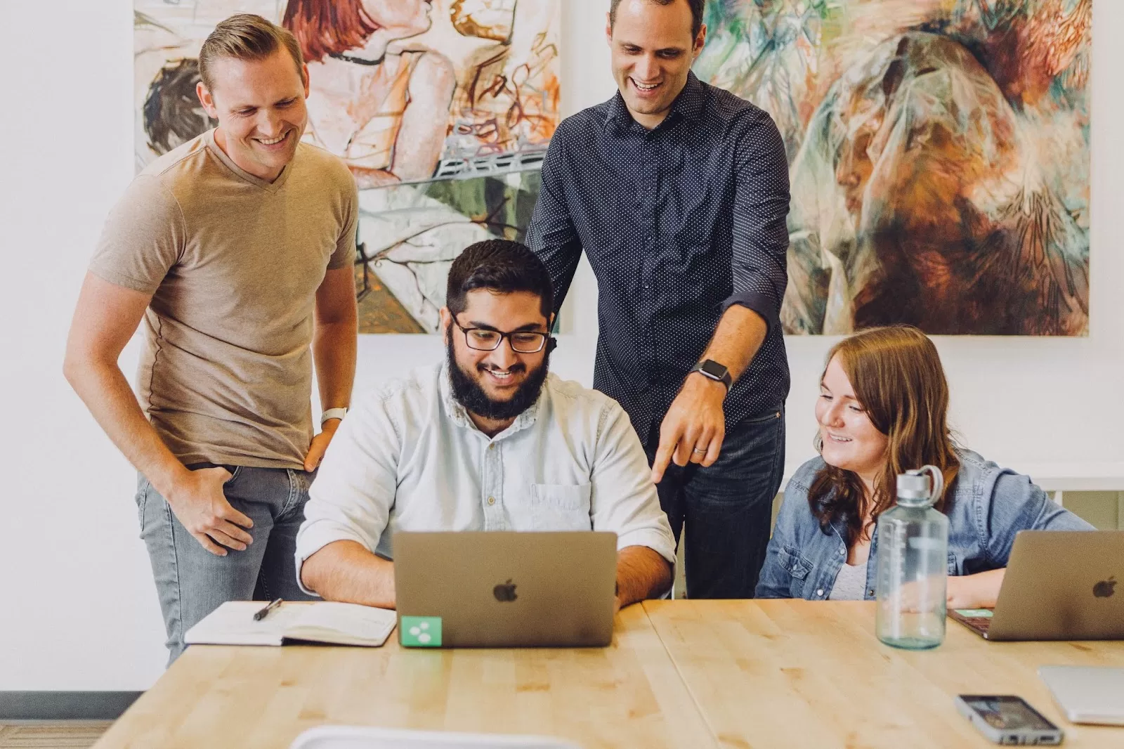 a group of people at an office space looking at a laptop screen