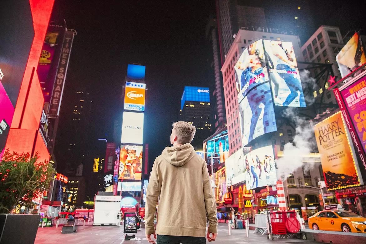 A person on Times Square at night looking at the billboards