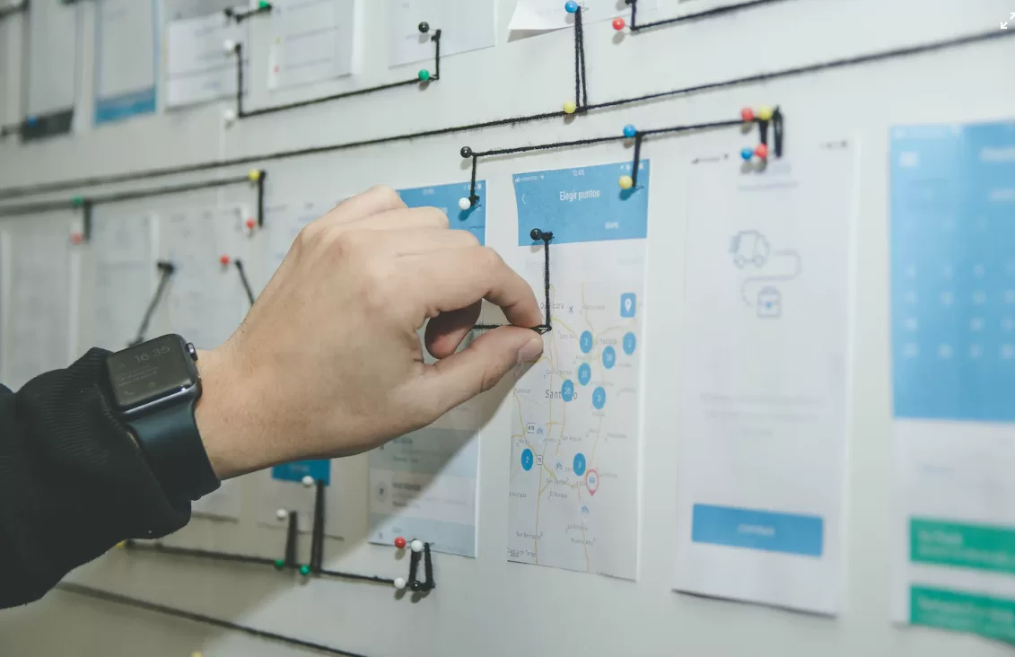 A person connecting sheets of paper on the wall into a board